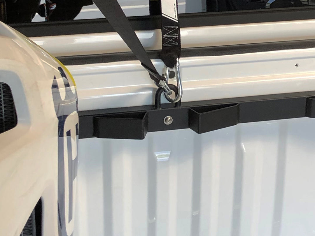 Close-up view of the Bed Buddy Moto Rack center wheel slot and center tie-down loop with tie-down straps connected to the loop on the rack.