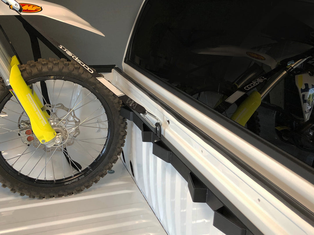 A Husqvarna dirt bike secured into the ed of a truck using the Bed Buddy Moto Rack.