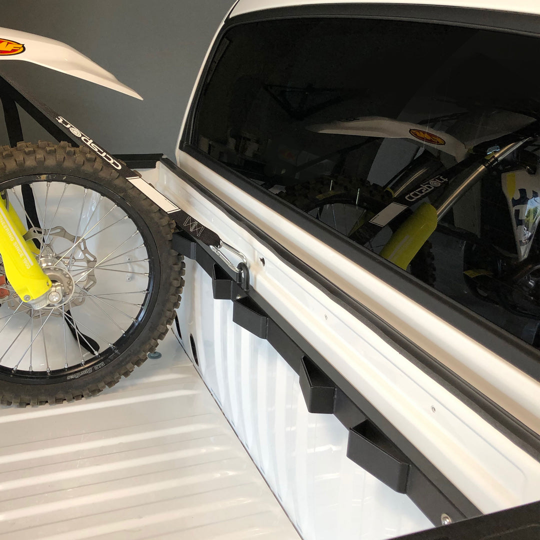 A motorcycle tie down to the Bed Buddy Moto Rack in the back of a truck.