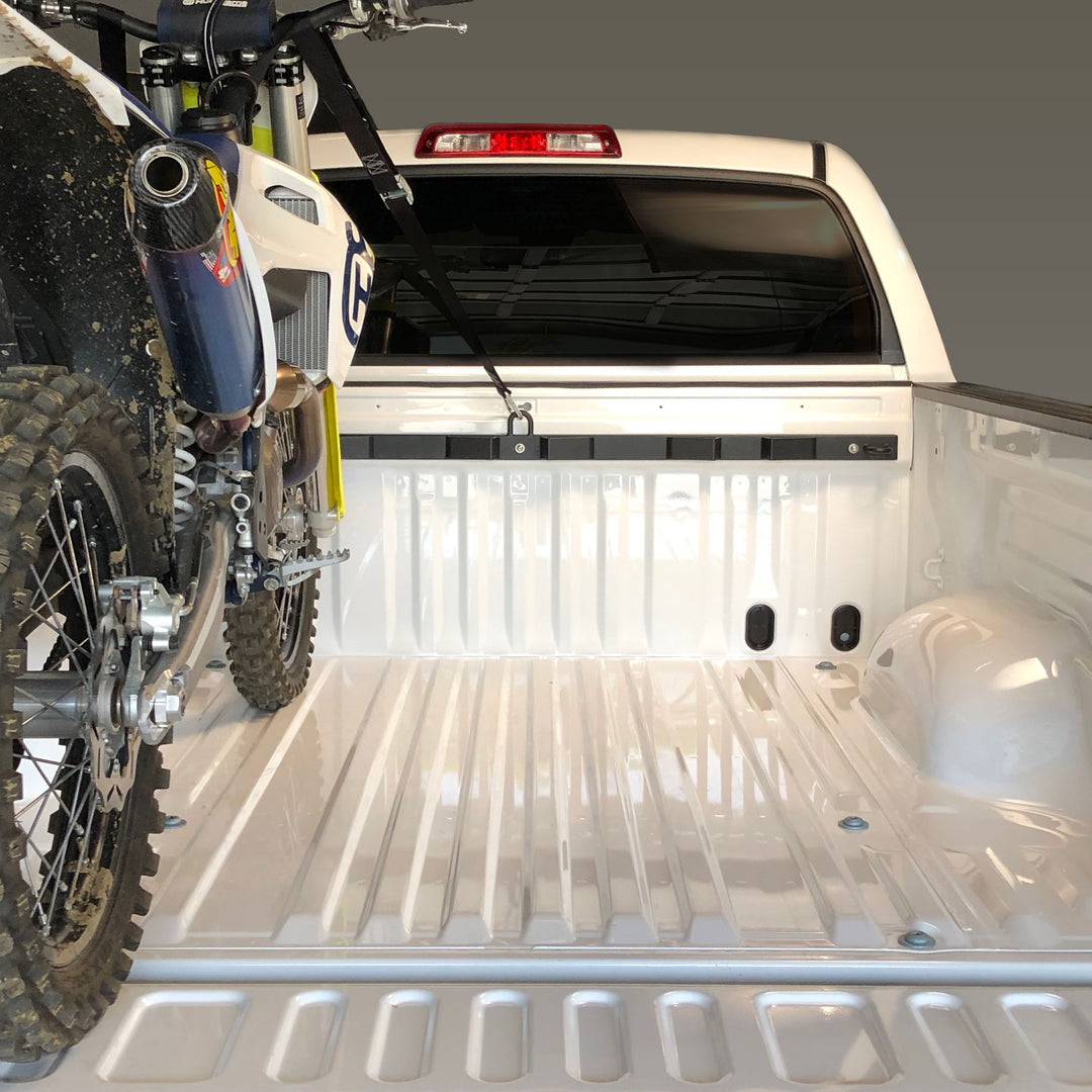Photo of a Husqvarna dirt bike tie down to the Bed Buddy moto rack in the cargo bed of a pickup truck.