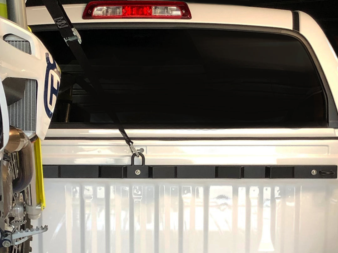 Forward view of a CCR Sport Bed Buddy Motorcycle Tie Down truck rack mounted across the front bulkhead of a truck with a single dirt bike tied down for transport.