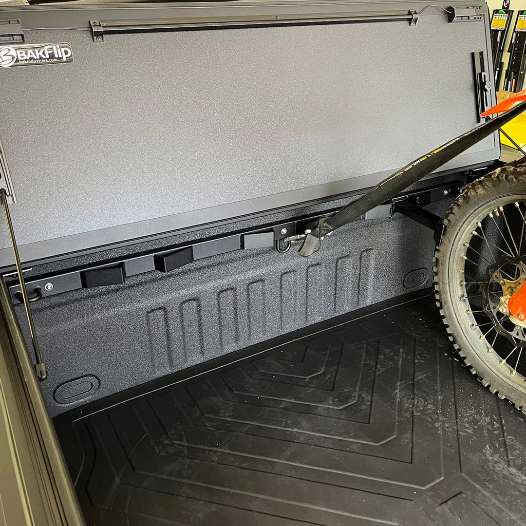 This image shows a Bed Buddy Offset Wheel Chock with a dirt bike offset from a BakFlip truck bed cover.