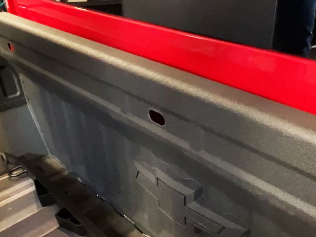 A Chevy Silverado truck bed showing the factory oval hole in the bulkhead.