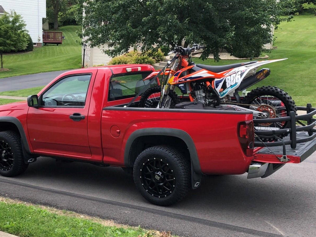 Red Chevy Colorado with an range Red bull KTM dirt bike in the back.