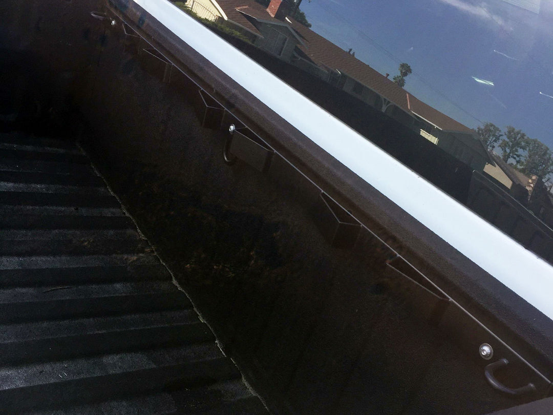 A black motorcycle tie down bar bolted into a truck bed.