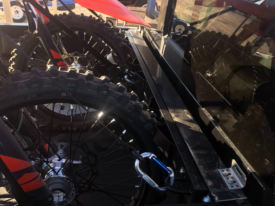 Two dirt bikes secured to a motorcycle rack in a truck bed.