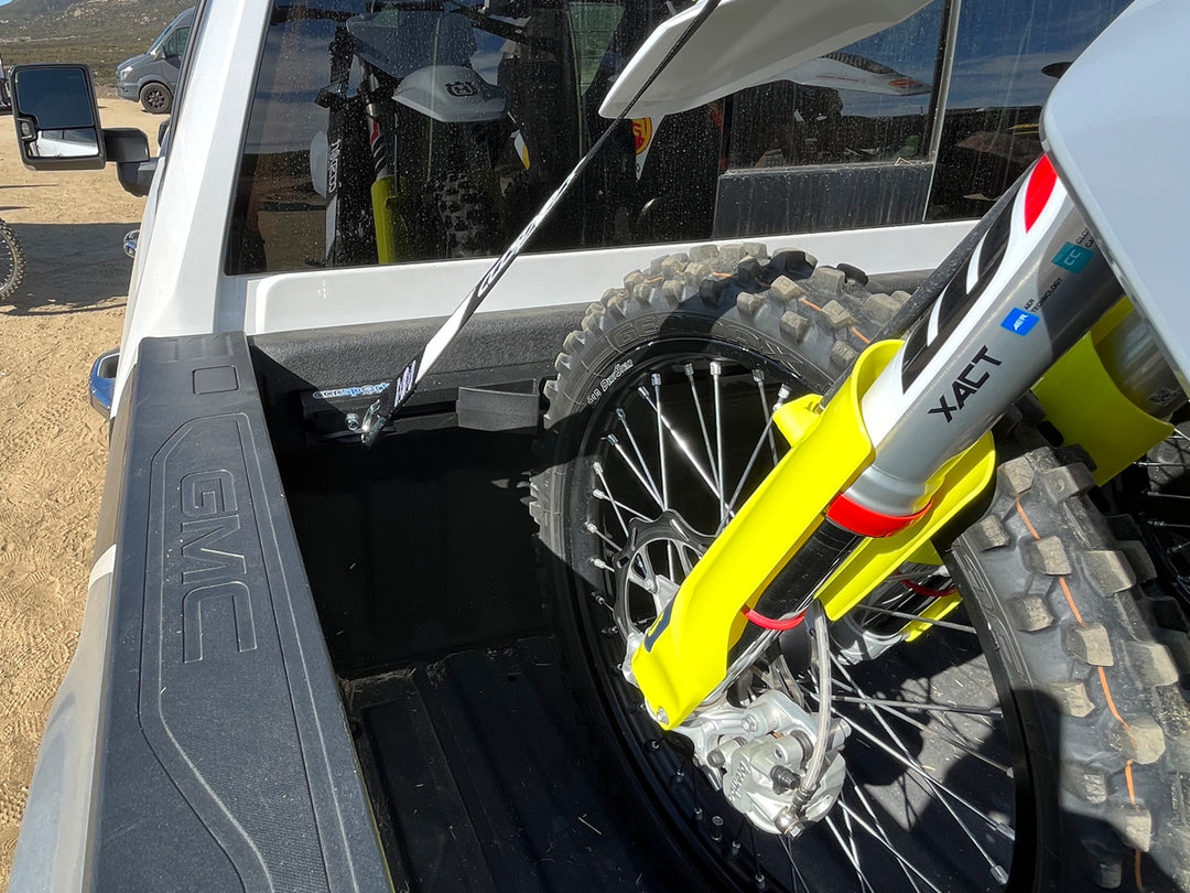 The Hybrid Moto Vise supporting the front knobby tire of a dirt bike in the bed of a Chevy truck.