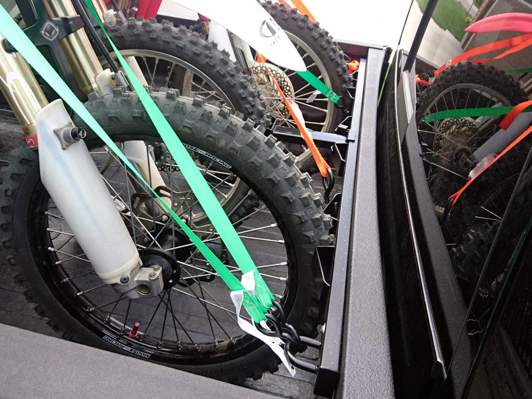 A side angle view of the CCR Sport Bed Buddy moto rack securing three motorcycles in the bed of a Dodge Ram truck.