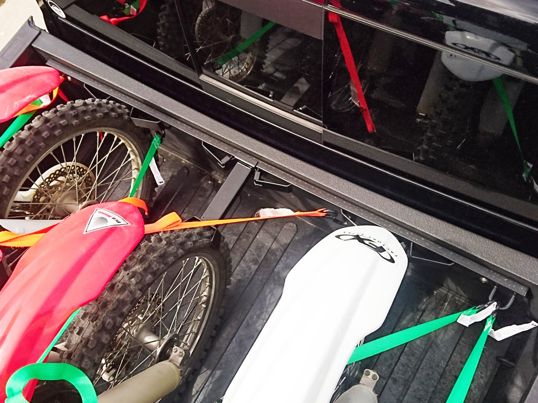 Three full size dirt bikes loaded into the bed of a Dodge Ram truck with the Bed Buddy Moto Rack and an offset wheel chock.