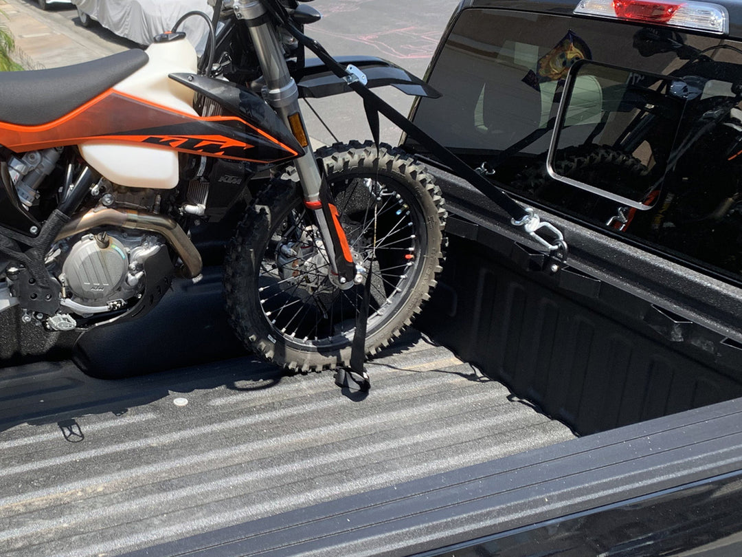 A KTM Dirt Bike strapped into the bed of a Ford F150 pickup.
