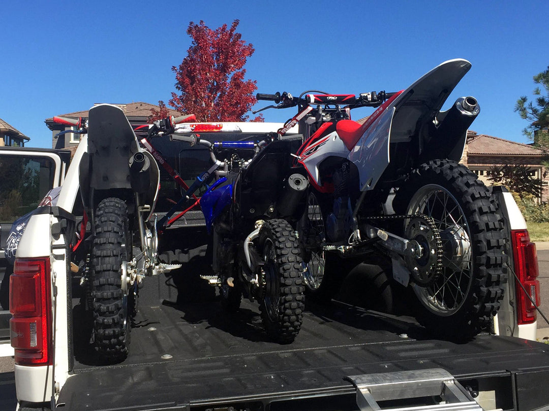 Three dirt bikes loaded into the bed of a Ford F150 with the Bed Buddy motorcycle tie down rack.
