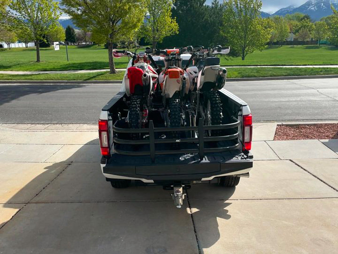 A Ford Super Duty loaded with three dirt bikes using the Bed Buddy Moto Rack tie down for support.