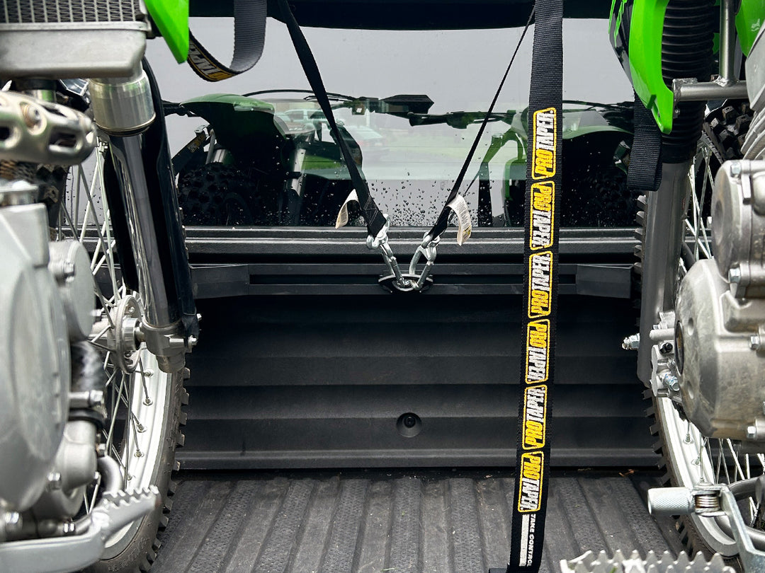 Two off-road motorcycles secured in a Honda Ridgeline truck bed using a CCR Sport motorcycle transport system.