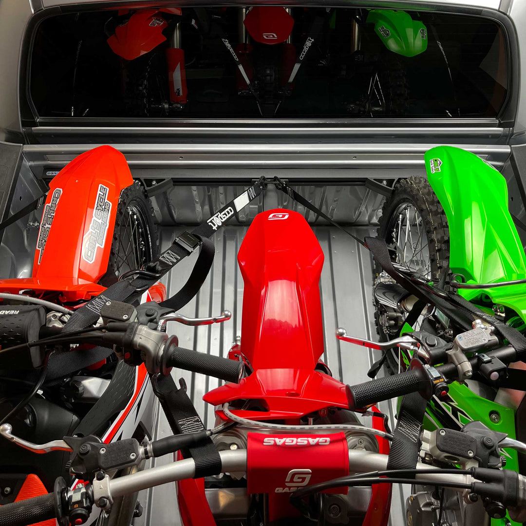This photo shows three dirt bikes loaded in the bed of a truck with the Offset Wheel Chock offsetting the middle bike to provide proper clearance from the two outside motorcycles.