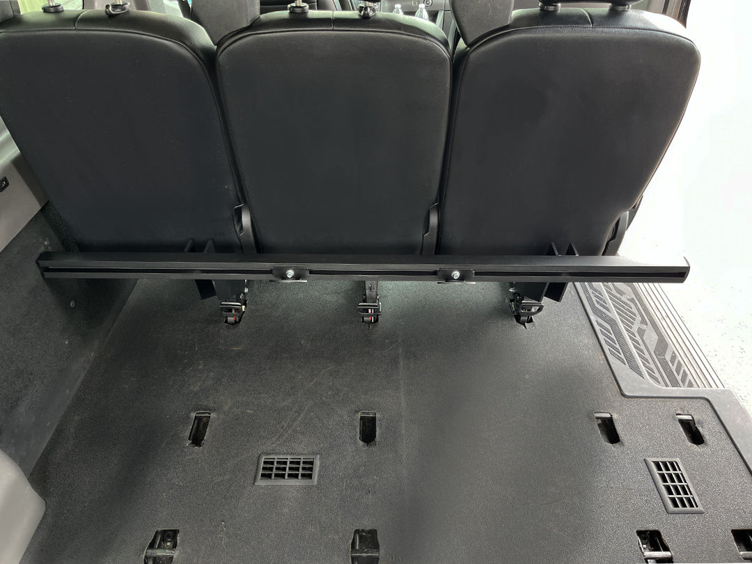 Forward facing view of the Hybrid Basic Rack mounted to the rear passenger seat of a Ford Transit van.