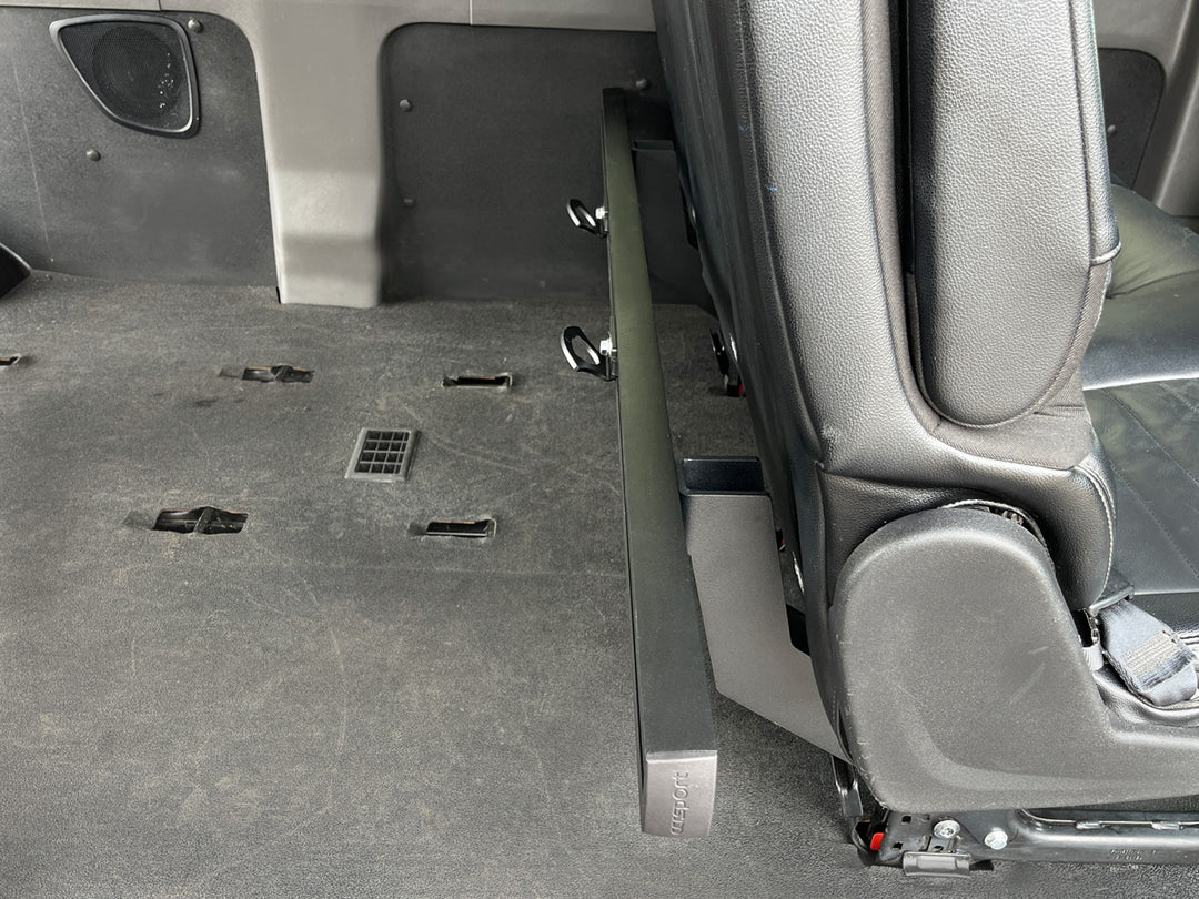 Side view of a cargo track system mounted to the rear passenger seat of a van.