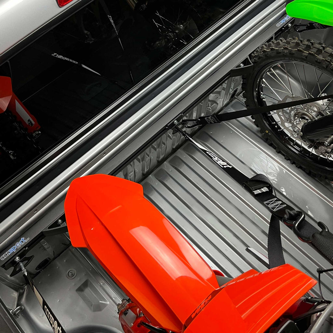 Image shows two motorcycles tie down to the Hybrid Moto Rack and utilizing the center anchor as attachment points for the inner straps of the bikes.