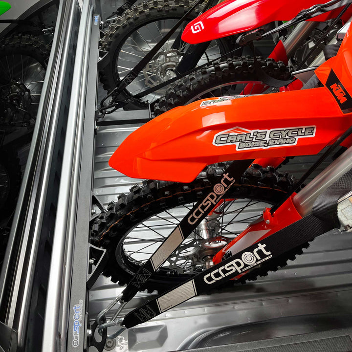 An image showing a front wheel view of three motorcycles being stabilized and tied into a truck bed with the Hybrid three bike rack system.