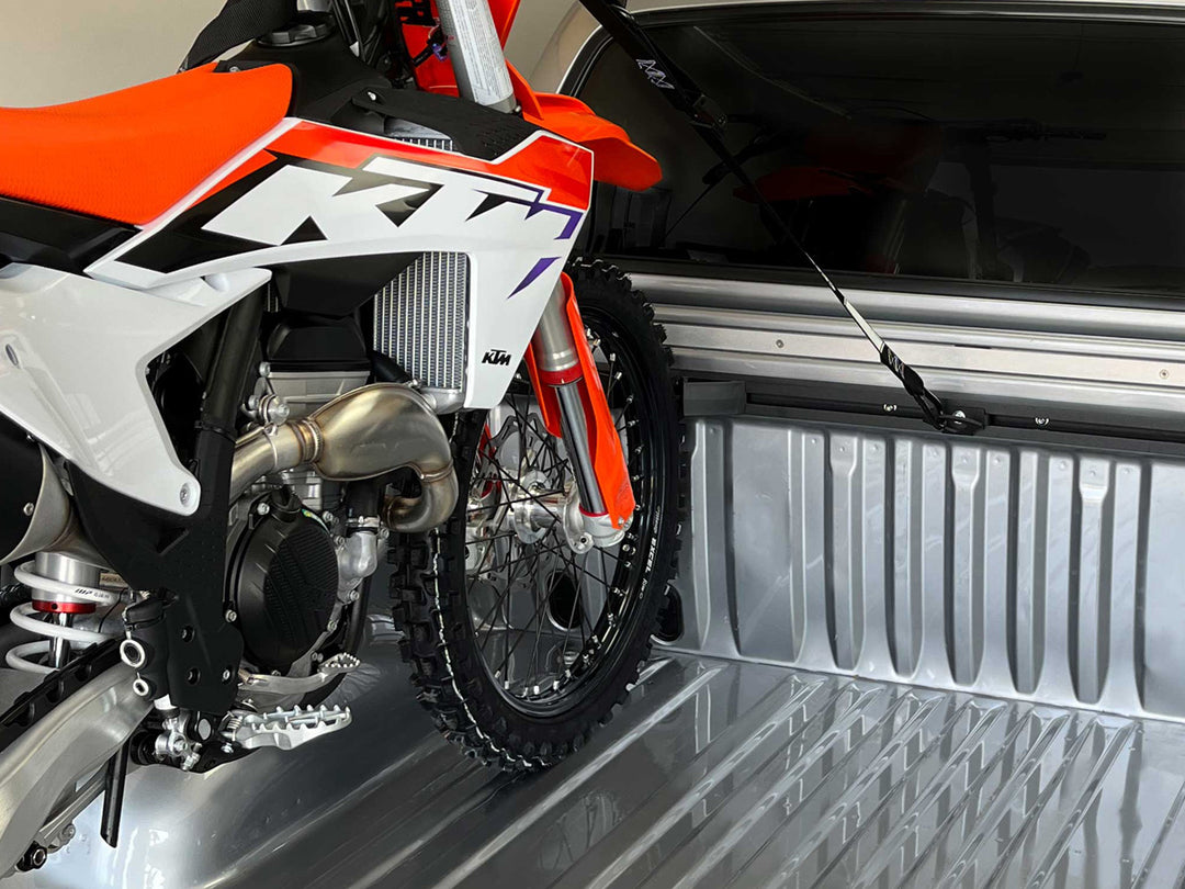A KTM dirt bike loaded in a truck bed and secured with the Hybrid Moto Rack.