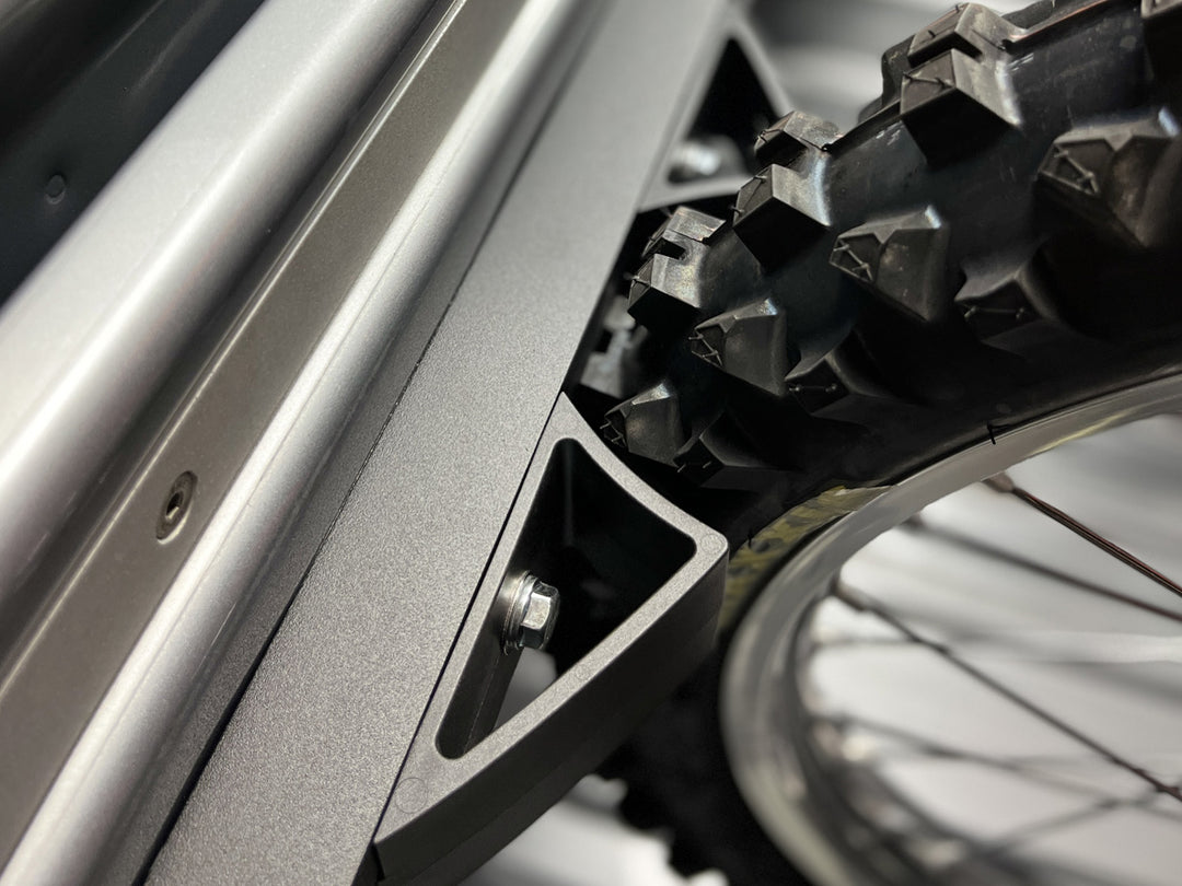 Extreme close-up of a knobby dirt bike tire secured with the Moto Vise wheel chock.