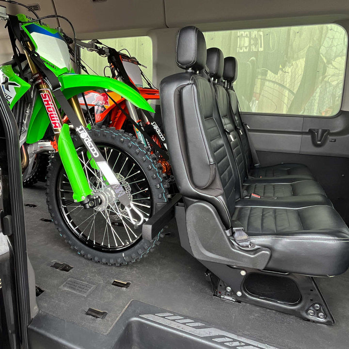 Two dirt bikes strapped to the rear passenger seat of a Mercedes Sprinter van using the CCR Sport Hybrid Moto Rack system 