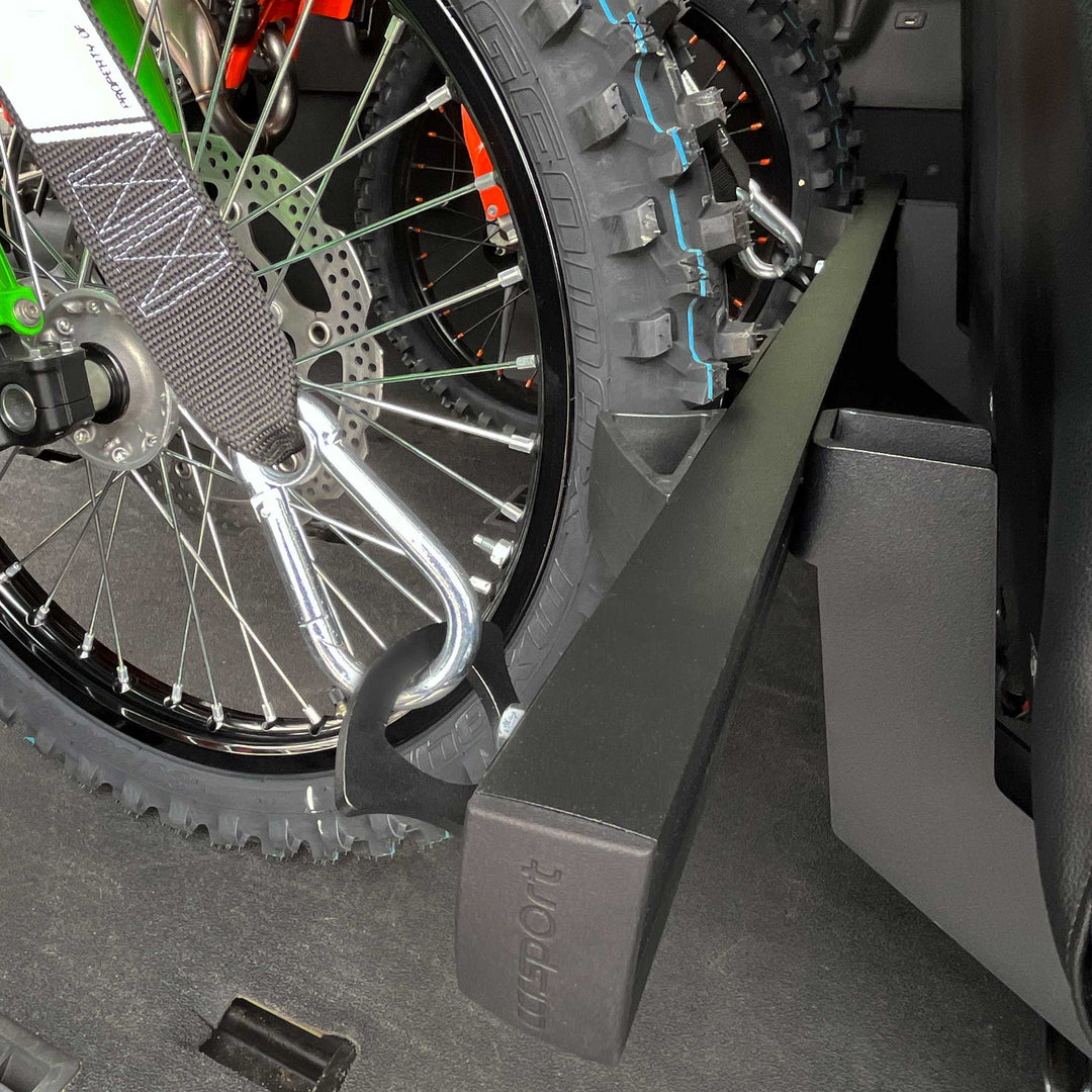 Close-up showing the front tire of a dirt bikes stabilized with the Hybrid Moto Vise wheel chock in a van.