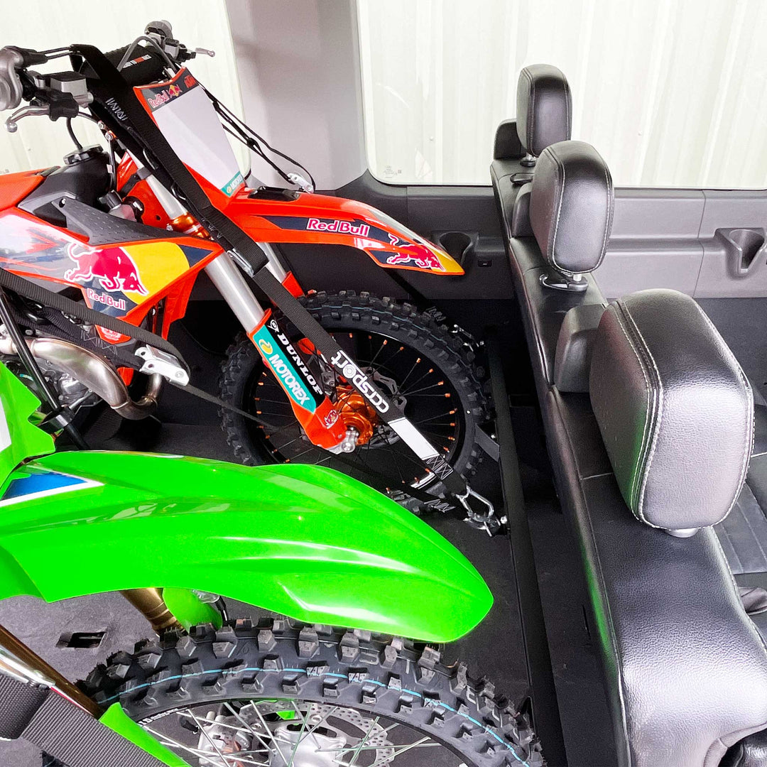 An upper side view showing two motocross dirt bikes secured with the Hybrid Moto Rack to a Mercedes Sprinterpassenger seat.