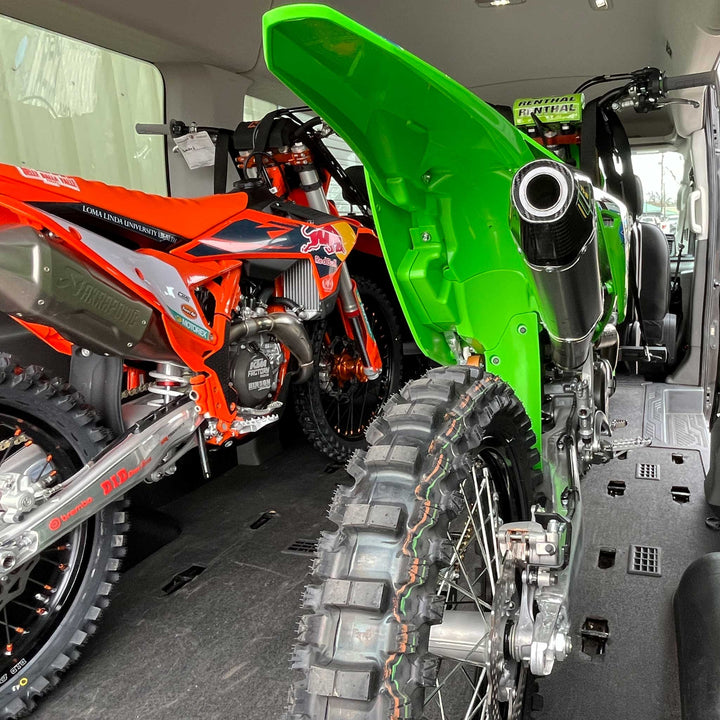A KTM and Kawasaki dirt bikes inside of a moto van.