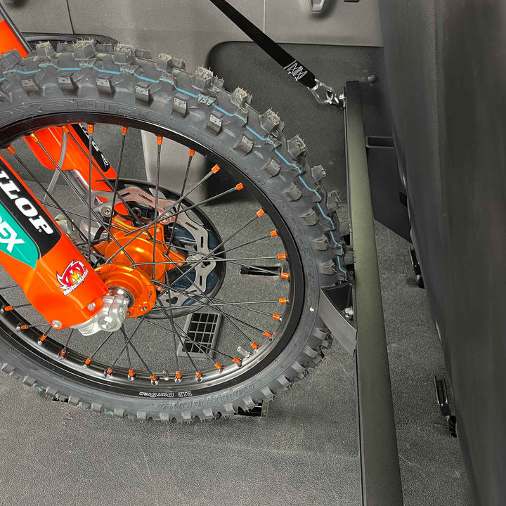 A close-up of the dirt bike stabilized with the Moto Vise wheel chock in a Mercedes Sprintervan.