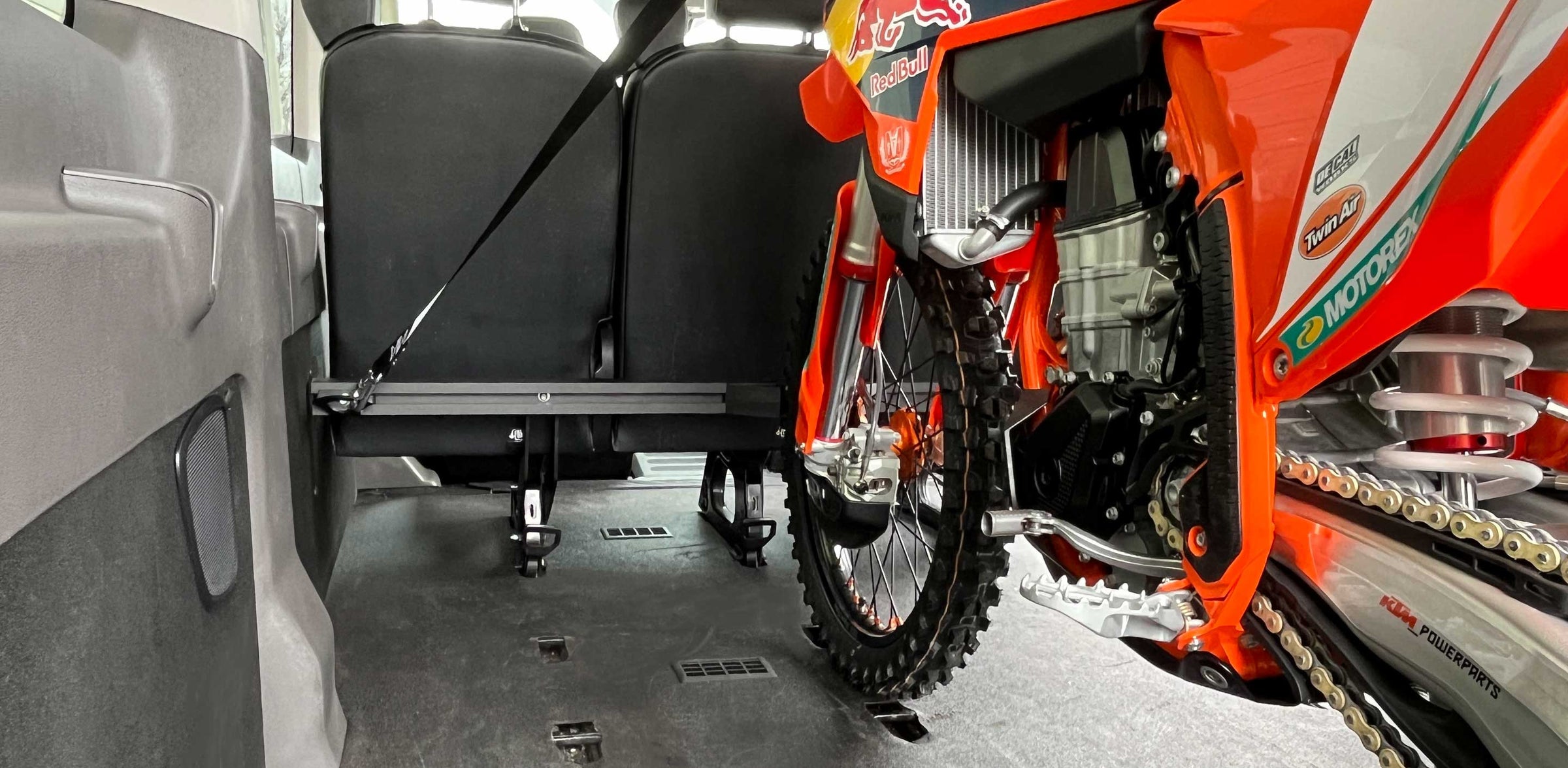KTM motocross dirt bike tie down to a motorcycle rack inside of a van.
