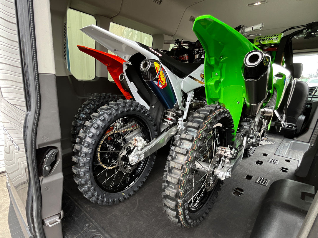 Rear angle of three dirt bikes loaded into a van.