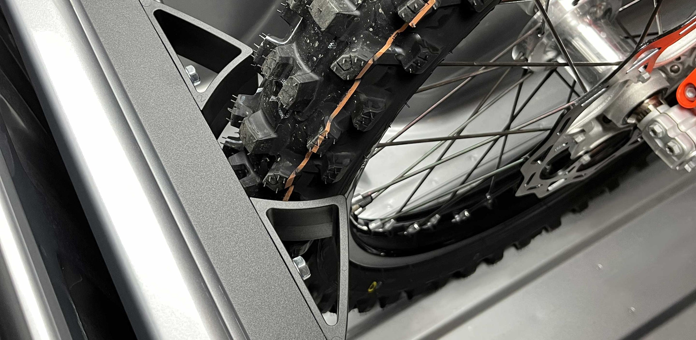Close-up of the front tire of a dirt bike secured with the Hybrid Moto Vise motorcycle wheel chock.