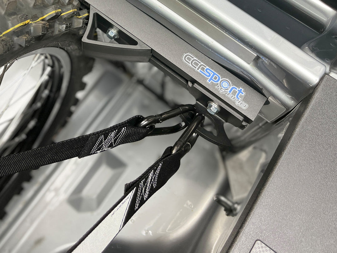 Top down view of a truck bed tie down rack with straps secured to an anchor