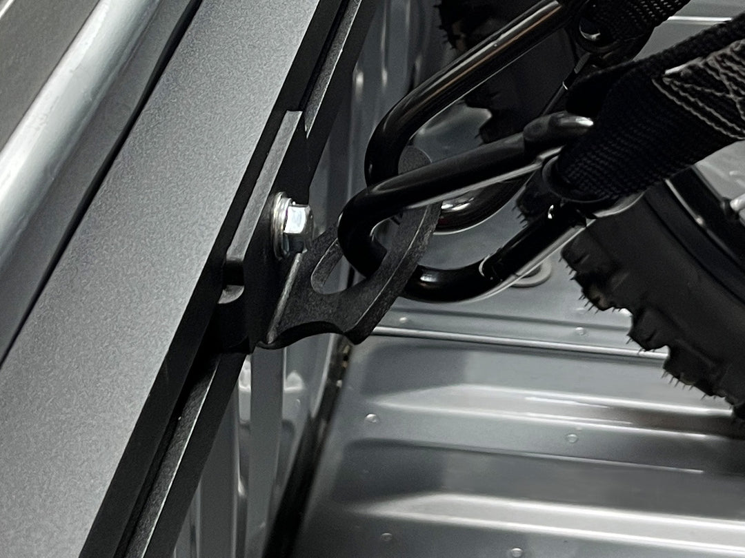 Very tight close-up of truck bed tie down anchor with carabiner straps attached.