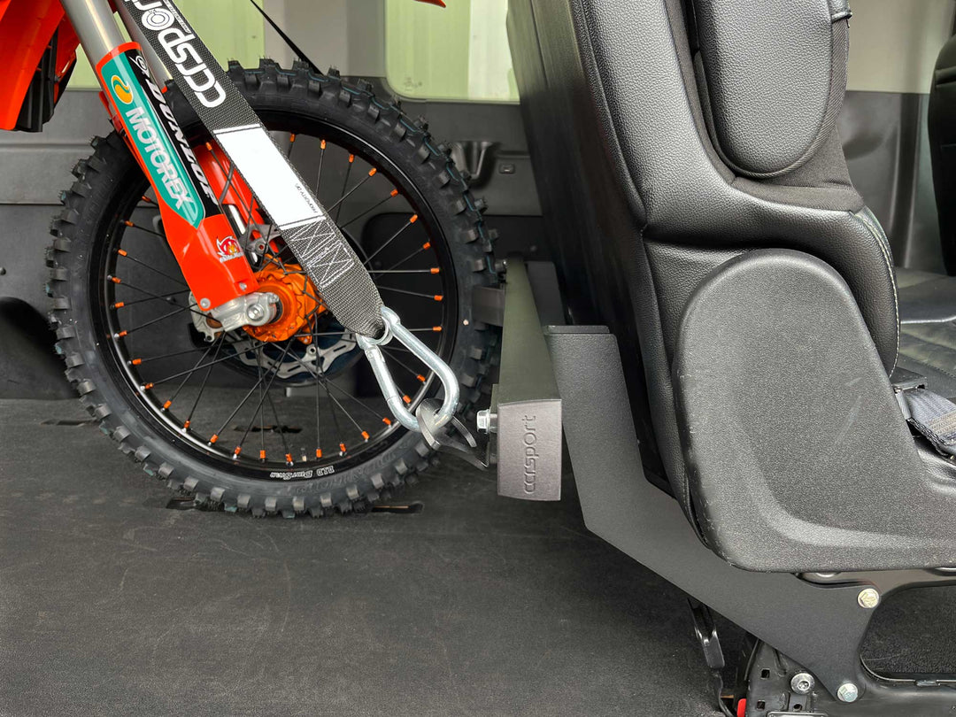 A close-up shot of a dirt bike tied down to the Hybrid Transit Van rear passenger seat rack system.