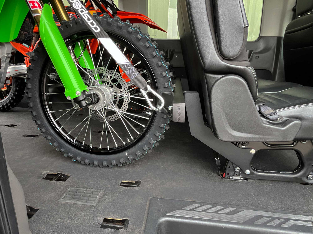 A close-up shot of a dirt bike tied down to the Hybrid Transit Van rear passenger seat rack system.