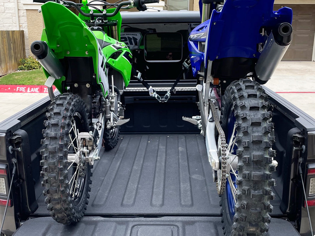 Two off-road motorcycles secured in a Jeep Gladiator truck bed using a CCR Sport motorcycle transport system.