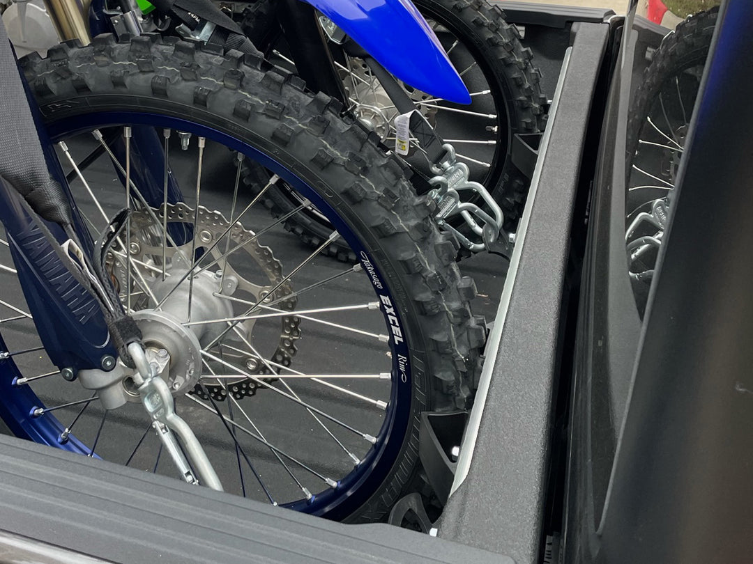 Two off-road motorcycles secured in a Jeep Gladiator truck bed using a CCR Sport motorcycle transport system.