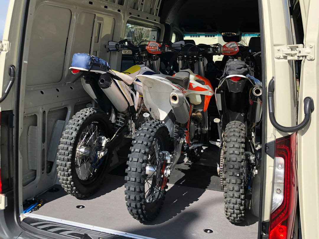 Three off-road motorcycles loaded and secured inside a Mercedes Sprinter van using a CCR Sport motorcycle transport system.