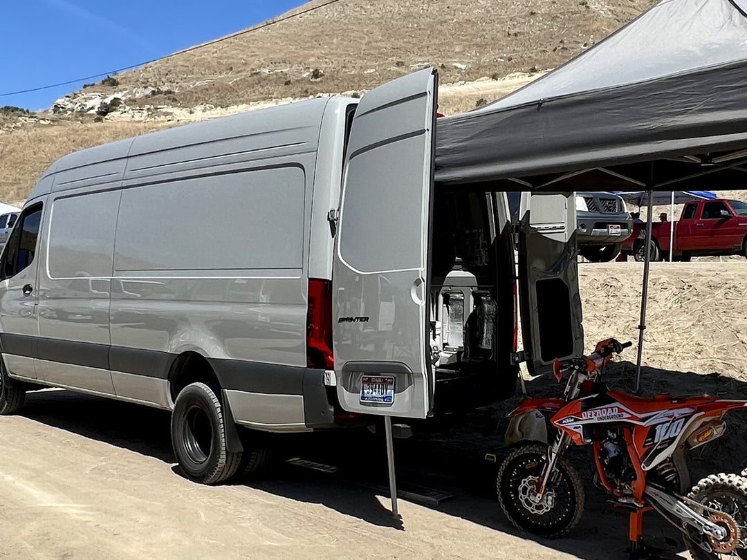 A Mercedes Sprinter van parked at a motocross track.