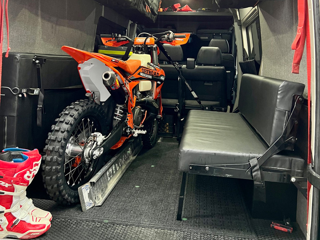 A dirt bike tied down in the rear of a Mercedes Sprinter van.
