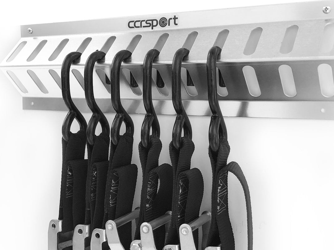 Aluminum tie down strap holder with six straps hanging in position.