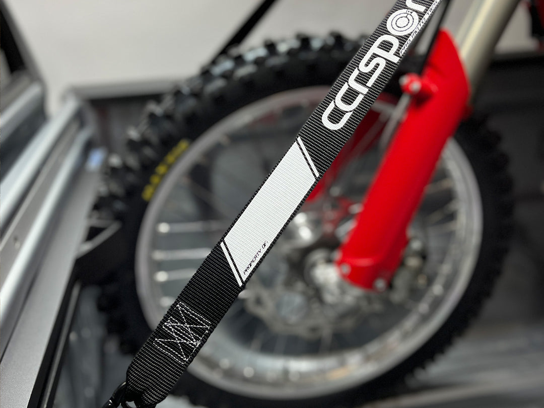 Close-up studio image of a ti-down strap securing  motorcycle in the bed of a truck.