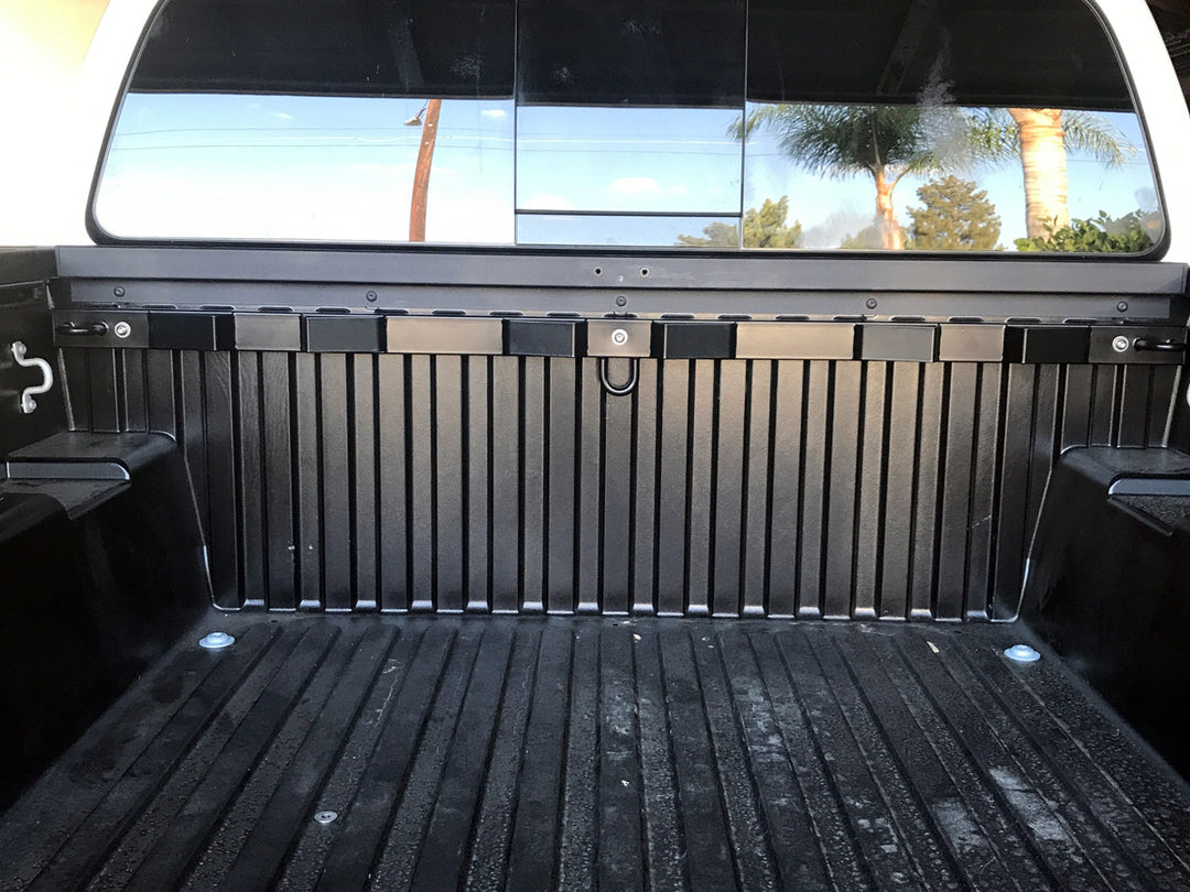 A straight on view of the Bed Buddy Moto Rack mounted to the front bulkhead of a Toyota Tacoma truck bed.