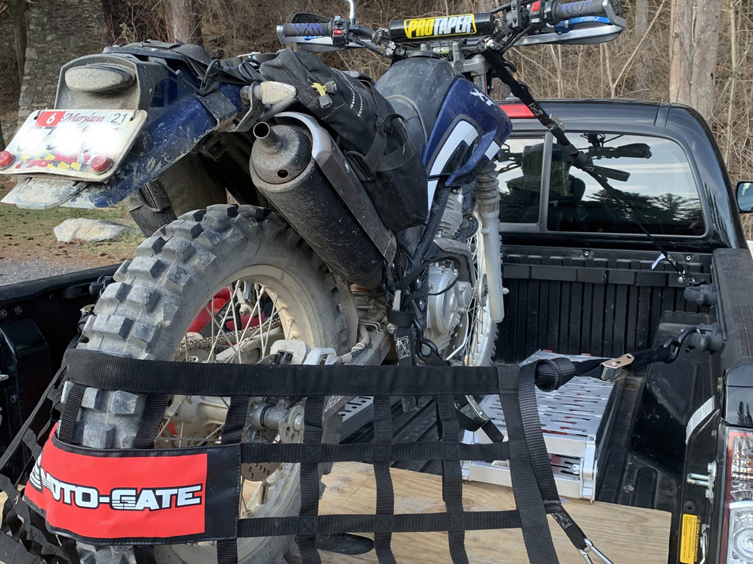 The Bed Buddy moto rack mounted in the bed of a Toyota Tacoma truck with a dual-sport motorcycle tied down for transport.