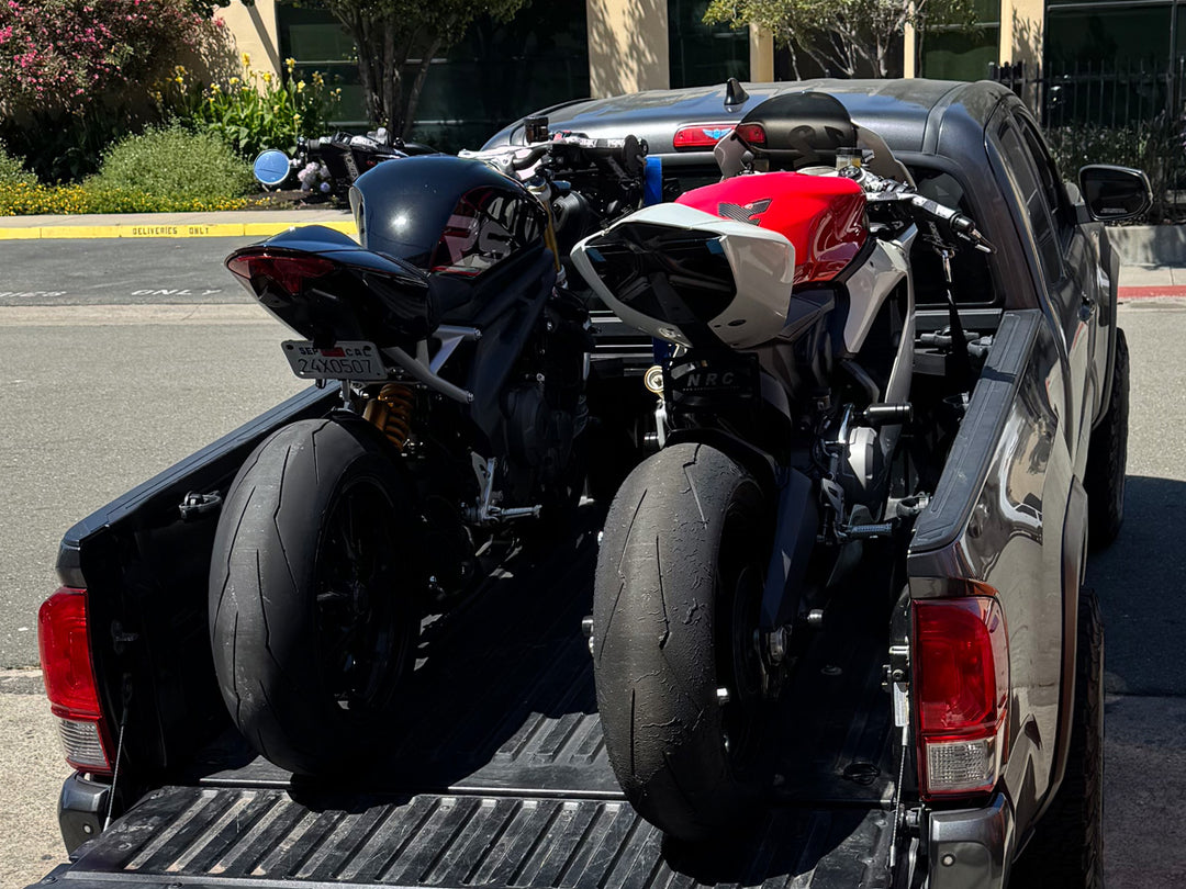 Two sport bikes loaded in the bed of a Toyota Tacoma.