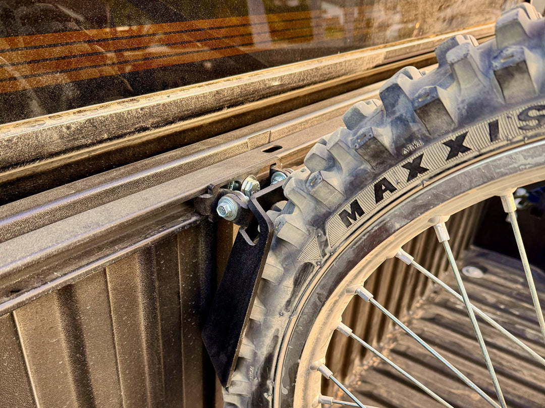 Close-up angle of a motorcycle front knobby tire held in place in a Toyota truck using the CCR Sport Pivot Chock.