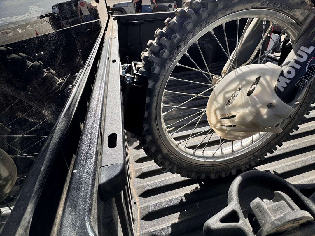 A side view of the CCR Sport Toyota Deck Rail Pivot Chock holding the front tire of a dirt bike.