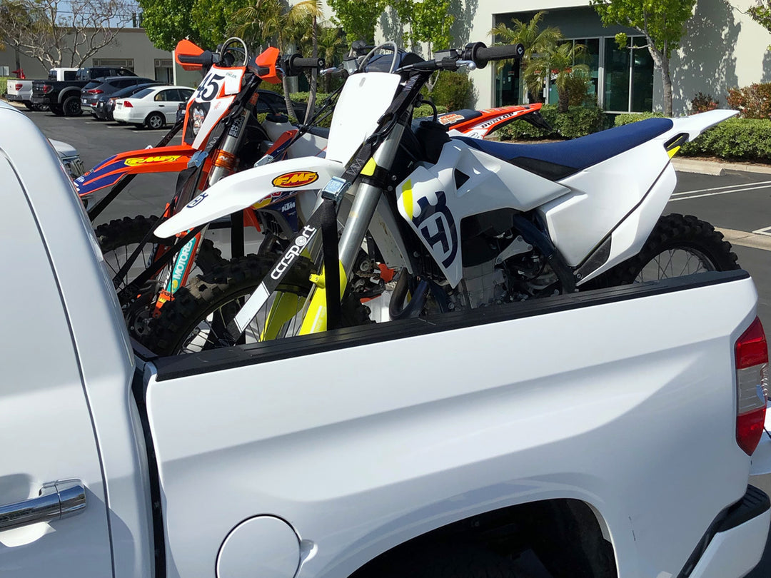 Dirt bikes loaded in the bed of a truck.