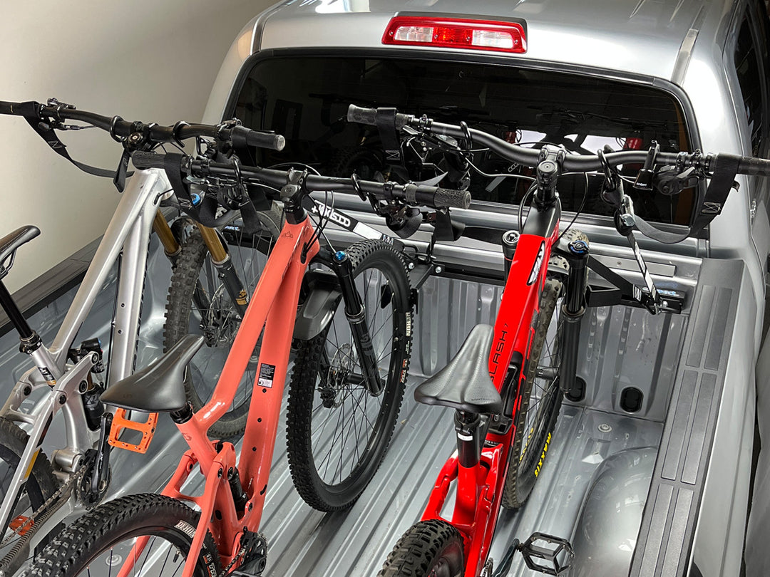 Three mountain bikes strapped securely into the bed of a truck using the CCR Sport Hybrid Moto Rack in a truck bed.